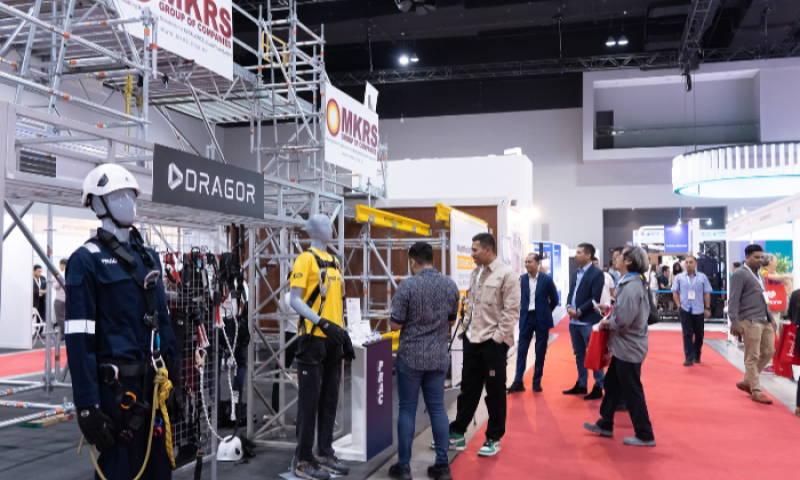 Visitors walking the BuildXpo exhibition floor past safety equipment displays